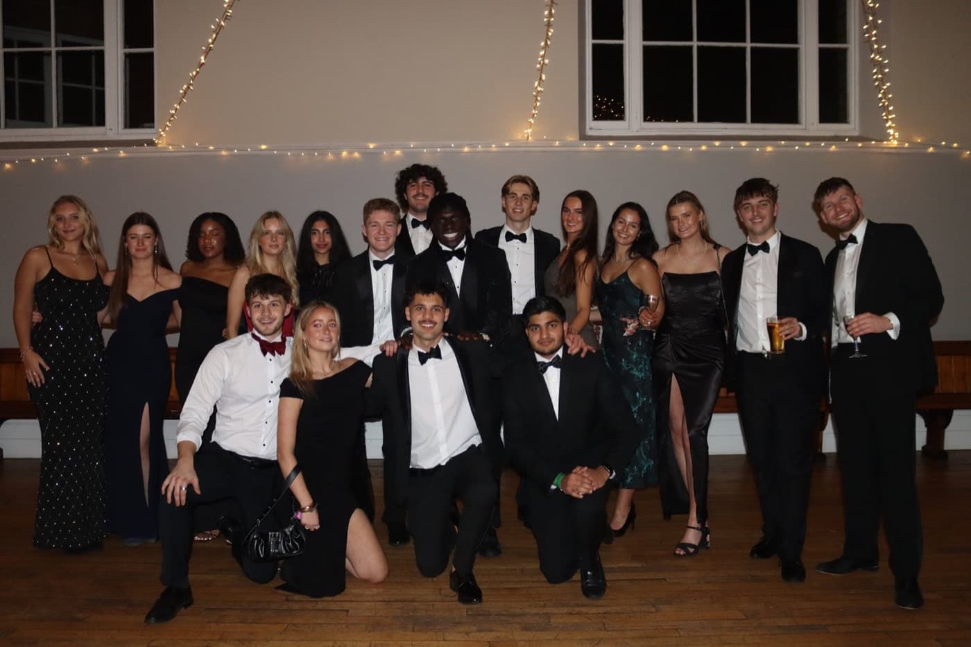 A large group of members in black tie together at a ball